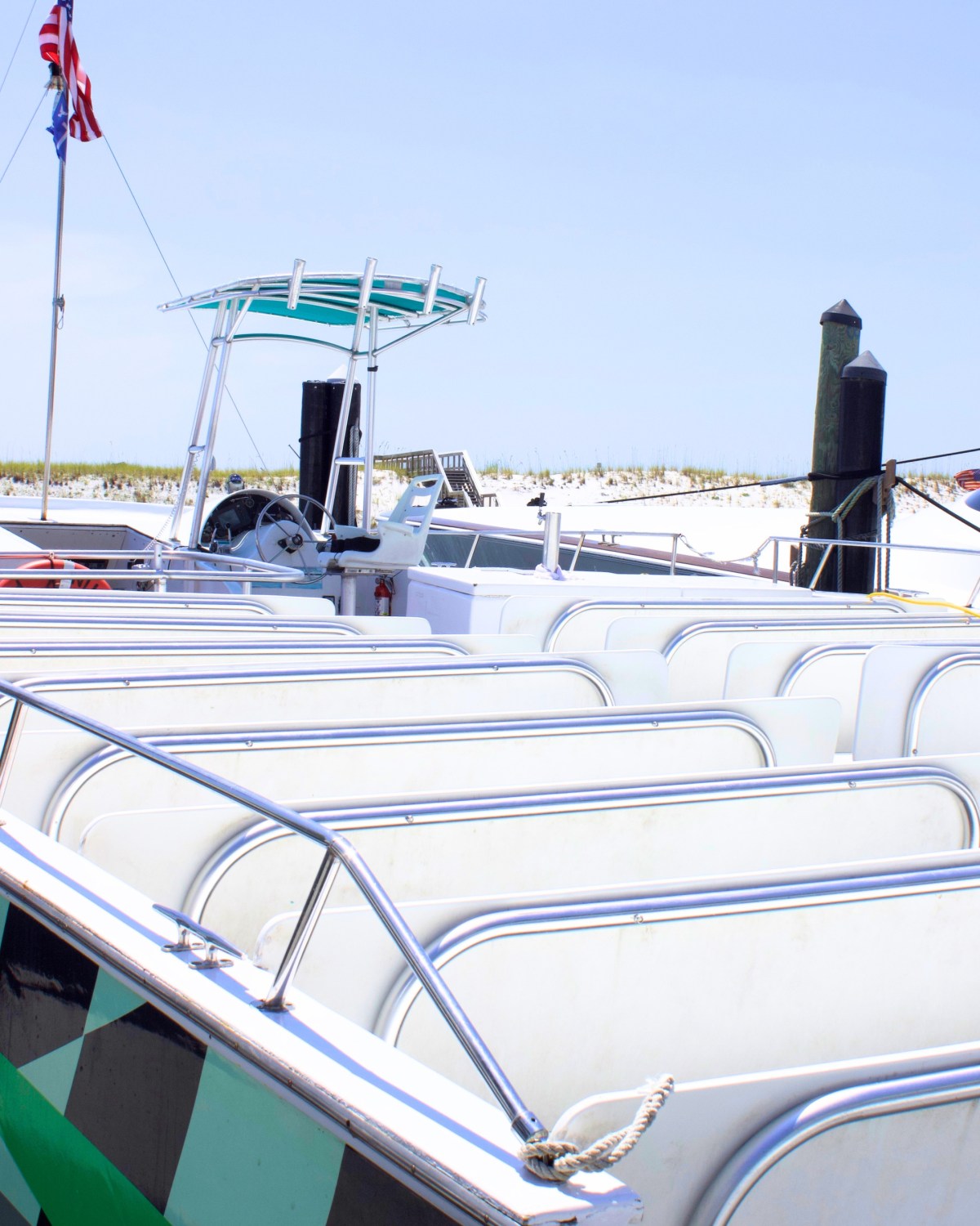 Empty passenger boat with white seats at a dock, U.S. flag in background.